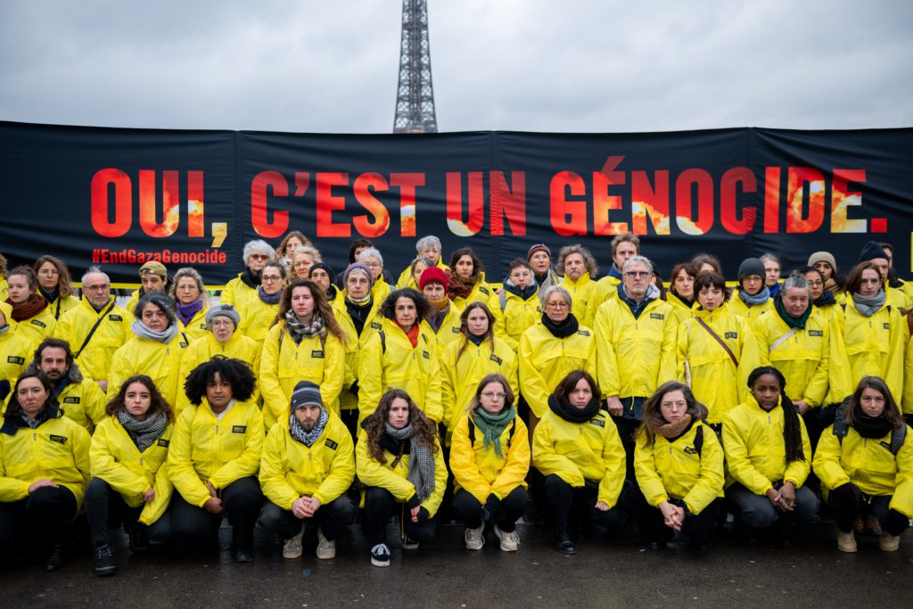 People from Amnesty France stand before a banner reading "Yes, it is a genocide." in French to protest the genocide in Gaza.
